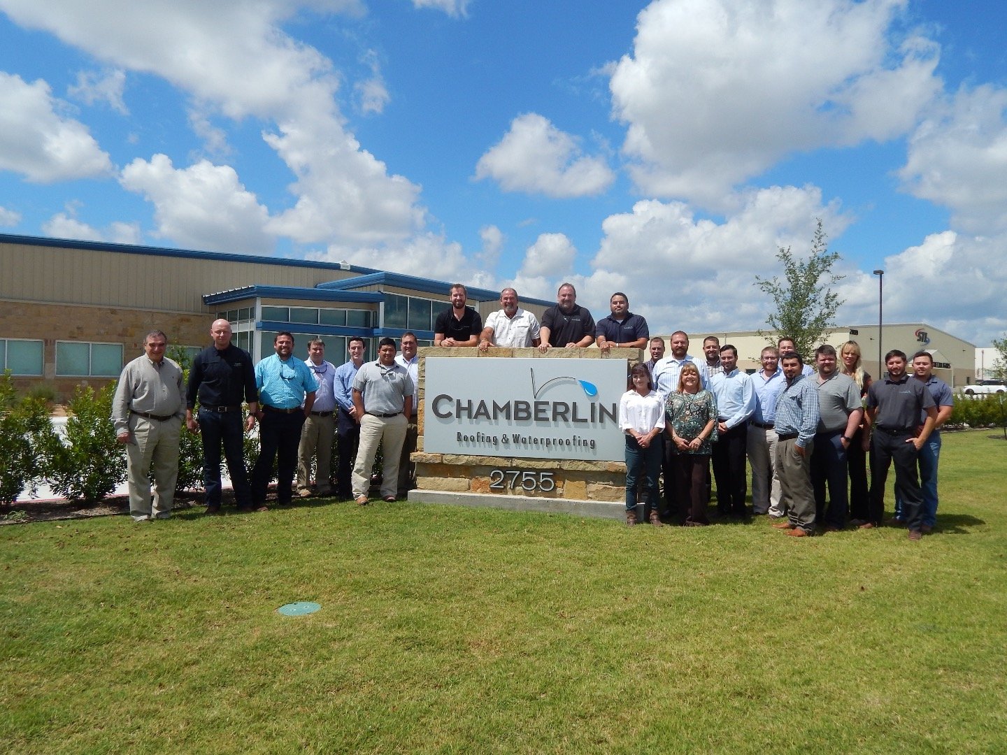 Chamberlin employees in front of exterior sign of new office in Buda Texas